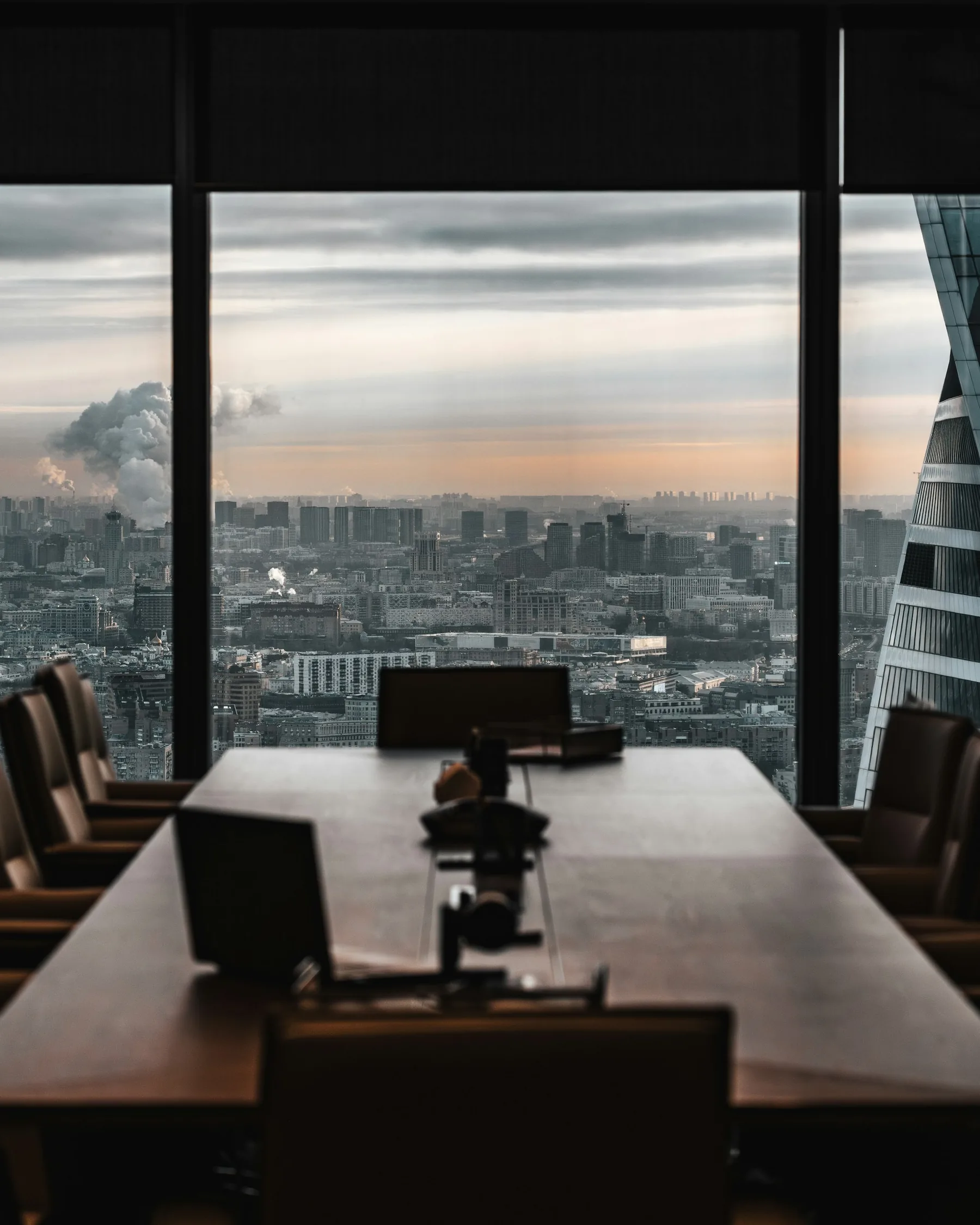 Sala de juntas en penumbra con vistas a la ciudad al atardecer